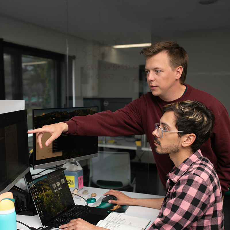 One person types as another points at a monitor.