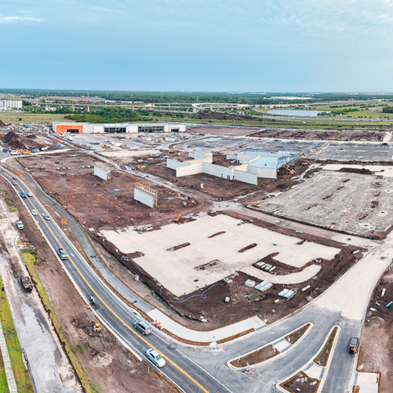 Aerial view of construction site with buildings, machines, and roads.
