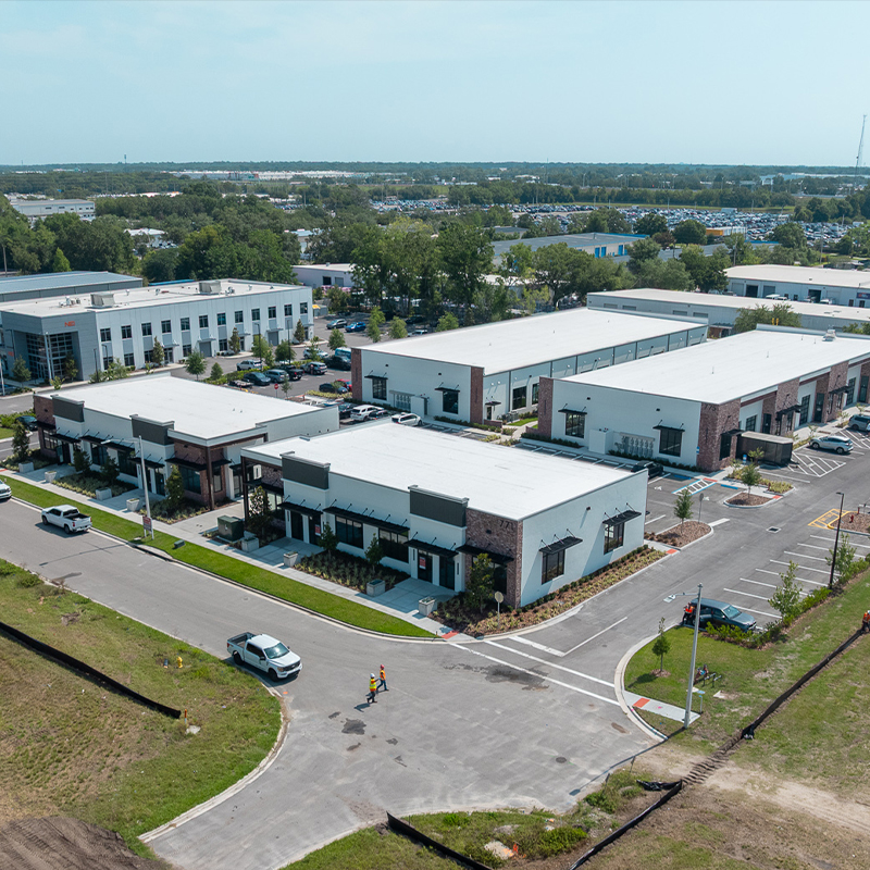 Aerial view of white office and warehouse buildings with cars.